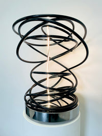 Illuminate your space with Mark Beattie's White in Tall Black Spiral, a unique sculpture featuring dimmable LED white light and painted copper on a mirror-polished stainless steel plinth. This one-of-a-kind masterpiece, measuring 67 x 54 x 52cm, is a captivating blend of light, texture, and contemporary design. Explore the artistic brilliance of White in Tall Black Spiral, available in different LED colors to suit your personal style and preferences.