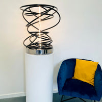 Illuminate your space with Mark Beattie's White in Tall Black Spiral, a unique sculpture featuring dimmable LED white light and painted copper on a mirror-polished stainless steel plinth. This one-of-a-kind masterpiece, measuring 67 x 54 x 52cm, is a captivating blend of light, texture, and contemporary design. Explore the artistic brilliance of White in Tall Black Spiral, available in different LED colors to suit your personal style and preferences.