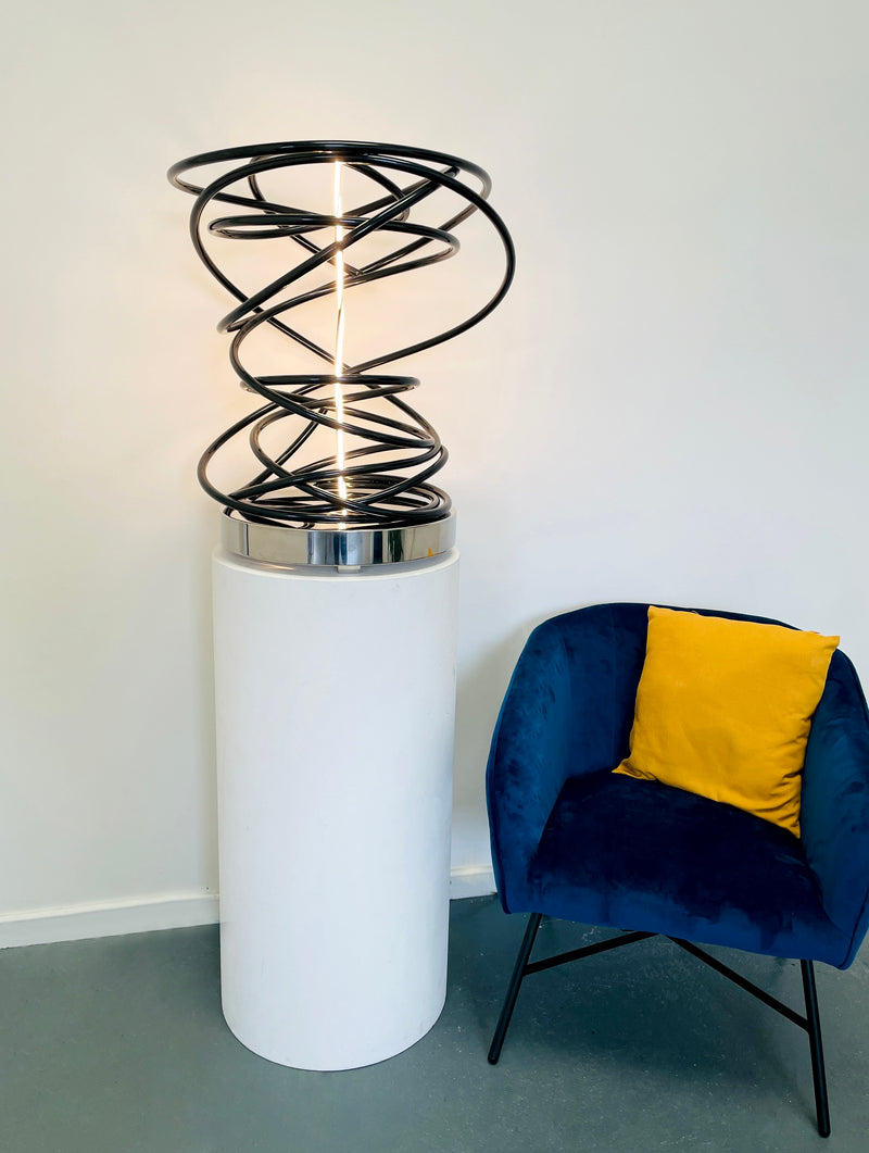 Illuminate your space with Mark Beattie's White in Tall Black Spiral, a unique sculpture featuring dimmable LED white light and painted copper on a mirror-polished stainless steel plinth. This one-of-a-kind masterpiece, measuring 67 x 54 x 52cm, is a captivating blend of light, texture, and contemporary design. Explore the artistic brilliance of White in Tall Black Spiral, available in different LED colors to suit your personal style and preferences.