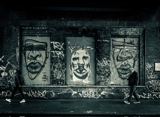 Fine art photography taken in Brixton under a bridge featuring graffiti and a man walking looking at this phone with a green tone 