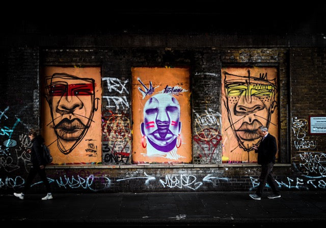 Fine art photography taken in Brixton under a bridge featuring graffiti and a man walking looking at this phone 