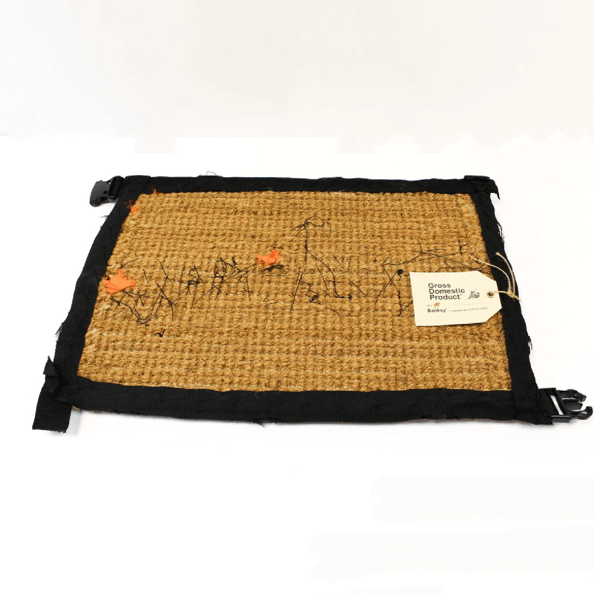 Buy Banksy merchandise online, Banksy for sale, Banksy Welcome Mat 2019, Banksy GDP 2019, Banksy Gross Domestic Product. Image is of a welcome mat, which is brown, stating 'welcome' in cursive writing. The item is distinctively rugged and rustic looking, with zips and safety belt buckles sticking out