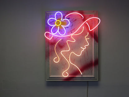 Add a burst of color to your space with Tony Spink's Doris. This one-of-a-kind artwork features multicoloured neon on a wooden backing painted white, presented in an ornate frame with splashes of vibrant hues. Measuring 61 x 82 cm, this original masterpiece is a unique fusion of neon art and ornate design. Elevate your space with this distinctive neon artwork, a lively addition to any art collection.