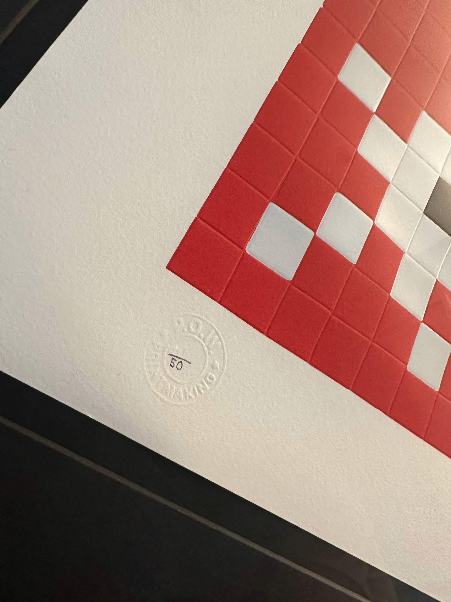 Invader Invasion red print in a black box frame close up of the pricture on walls stamp