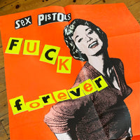 A zoomed in image of the Jamie Reid artwork 'Fuck Forever' laid on the floor. The artwork version has a red background, and lettering stating Sex Pistols Fuck Forever. 