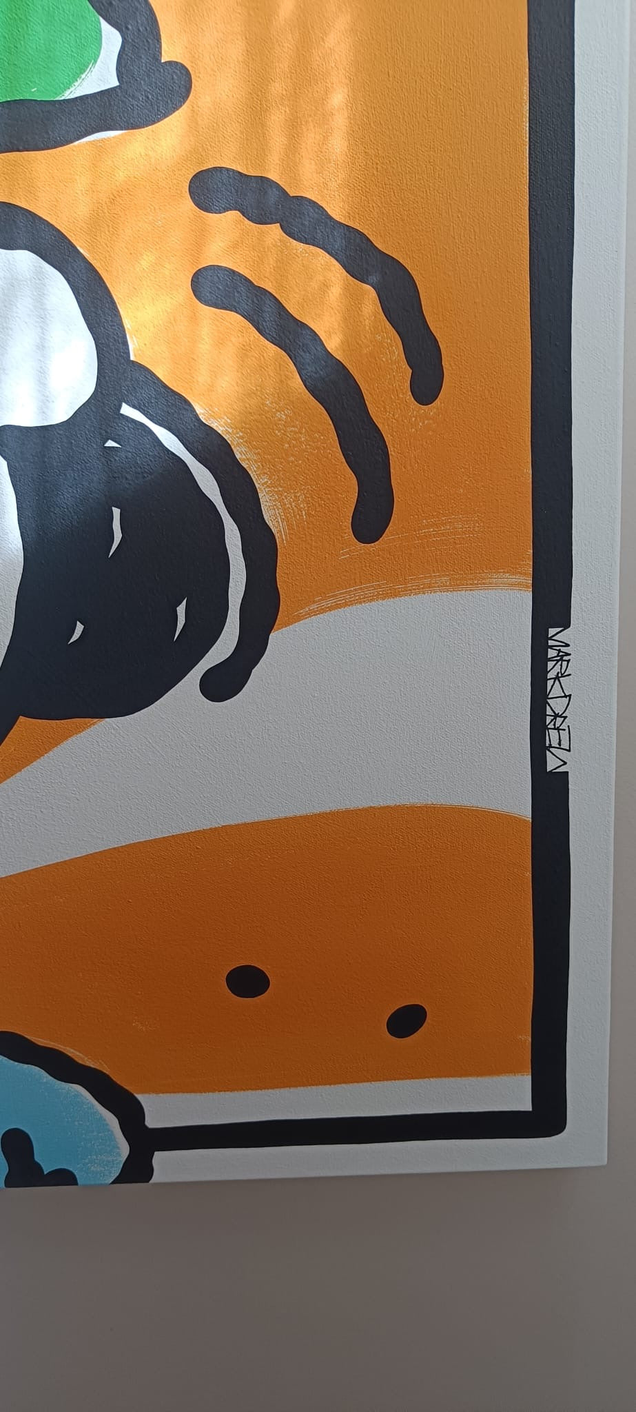 A close-up of a colorful abstract art print or poster showing bold black shapes, orange and white blocks, and a white border with a small vertical signature.