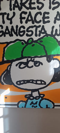 A close-up of a printed graphic featuring a Snoopy cartoon character with a green cap and blue shirt, with partial black text above on a white background.