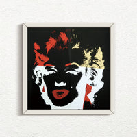 a sunday b morning print after andy warhol titled 'golden marilyn 39' in white frame. the artwork features a negative image of marilyn monroe's face on a black background, colourised in red, yellow, and white. this is a sunday b morning print for sale