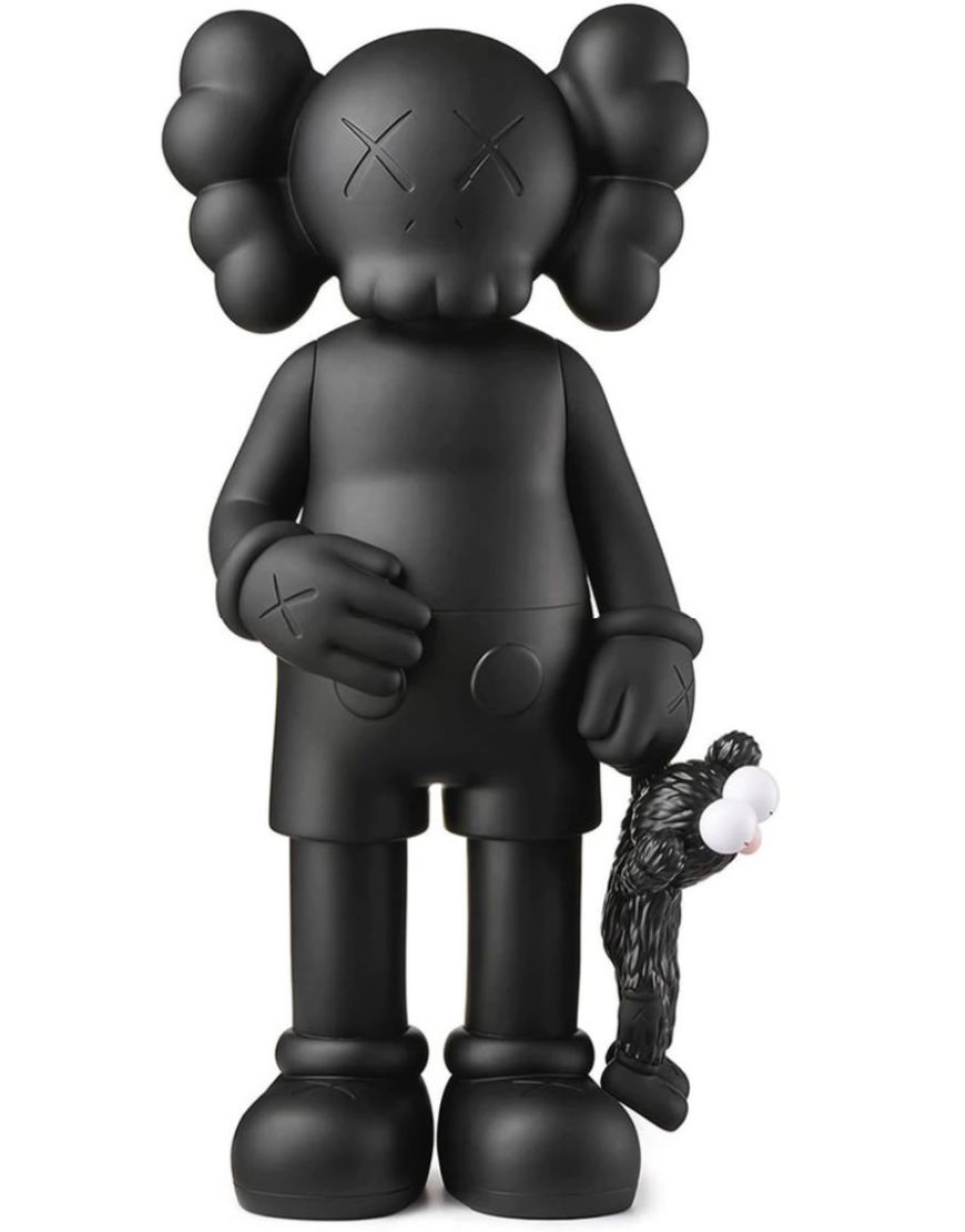 A matte black KAWS-style toy figure with a small black-and-white plush attached to one hand, photographed against a plain white background.
