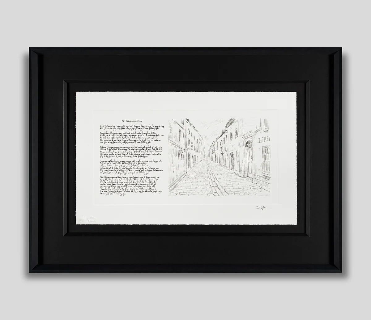 Framed black and white art print featuring a pencil-style sketch of a European street on the right and a block of text on the left, set in a black frame against a light gray background.