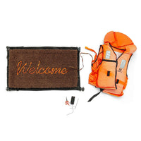 Buy Banksy merchandise online, Banksy for sale, Banksy Welcome Mat 2019, Banksy GDP 2019, Banksy Gross Domestic Product. Image is of a welcome mat, which is brown, stating 'welcome' in cursive writing. The item is distinctively rugged and rustic looking, with zips and safety belt buckles sticking out